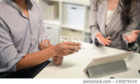 Close up of office workers reviewing data and sharing strategies on digital tablet 130879319