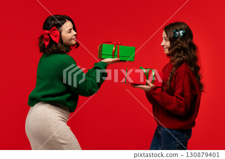 Mum and teenage daughter share red and green boxes, smiling 130879401
