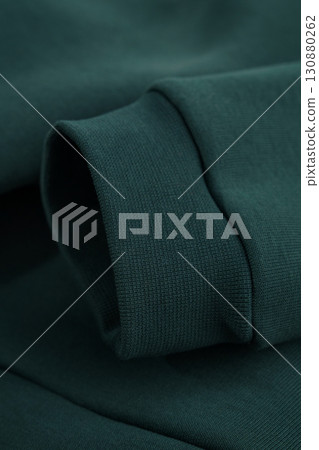 Hoodie texture. Close-up of dark green sweatshirt sleeve. Textile warm fabric macro background. Hoodie texture. Close-up of dark green sweatshirt sleeve. Textile warm fabric macro background. 130880262