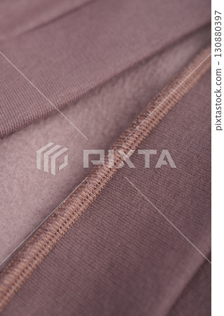 Brown textile with seam. Inner loop seam of clothing. Mocha cotton. Clothing with insulation on fleece. 130880397