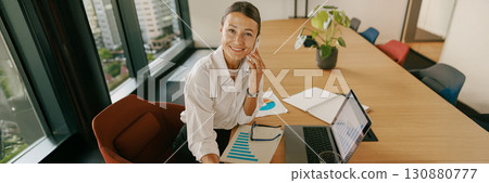 A Professional Woman Engaged in Tasks at Her Work in a Modern and Stylish Office Setting 130880777