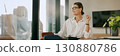 A confident businesswoman standing proudly in a modern office, showcasing her professionalism 130880786