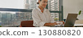 A woman is working diligently on her laptop in a contemporary and modern office space 130880820