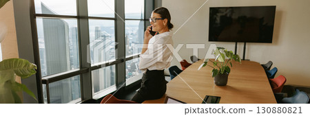 A professional woman is in her office making a crucial business call that may affect her career A professional woman is in her office making a crucial business call that may affect her career 130880821
