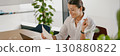 A Professional Woman Fully Engaged in Her Work Utilizing a Laptop and Various Documents 130880822