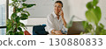 A professional businesswoman is working in a modern office environment while making a phone call 130880833