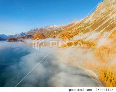 Drone view of a mountain valley with fog. The road along the lake shore. Drone view of a mountain valley with fog. The road along the lake shore. 130881147