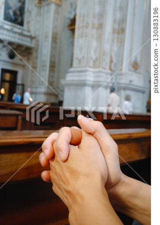 a man prays with clasped hands in a church a man prays with clasped hands in a church 130883196