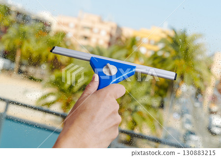 man removing soapy water from a window 130883215