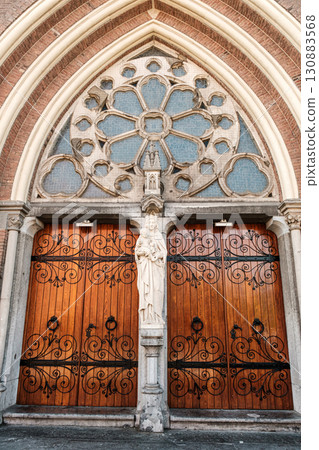 Ornate wooden church doors with intricate carvings and decorative stained glass elements 130883568