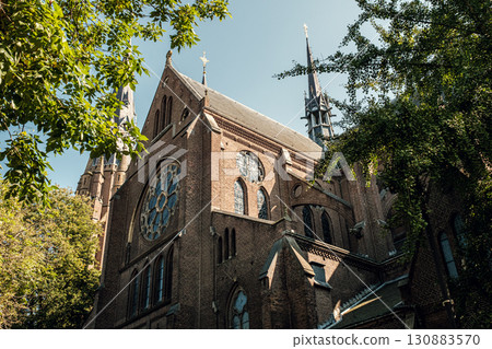 Historic church structure with intricate architecture surrounded by lush greenery and blue sky Historic church structure with intricate architecture surrounded by lush greenery and blue sky 130883570