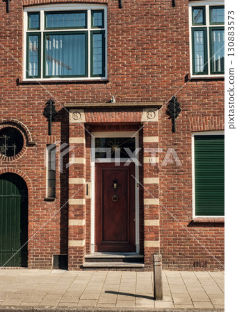 Elegant brick facade with wooden door and decorative windows showcasing architectural beauty 130883573