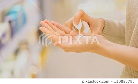 Female customer testing cream on hand while choosing skincare product in beauty store. Conscious choice, comparison, bodycare shopping. Woman selecting moisturizing cream at cosmetic shop. Female customer testing cream on hand while choosing skincare product in beauty store. Conscious choice, comparison, bodycare shopping. Woman selecting moisturizing cream at cosmetic shop. 130883795