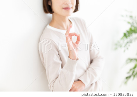 一位穿著休閒服的中年婦女靠在窗邊的白牆上，畫了一個圓圈 130883852
