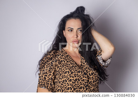 a woman with long hair, wearing a leopard print top, and she is posing  130884030