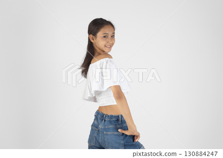 Young woman in white crop top and jeans posing confidently. Young woman in white crop top and jeans posing confidently. 130884247