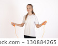 A young girl stands holding a jump rope, ready for exercise 130884265