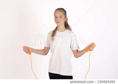 A young girl stands holding a jump rope, ready for exercise A young girl stands holding a jump rope, ready for exercise 130884265