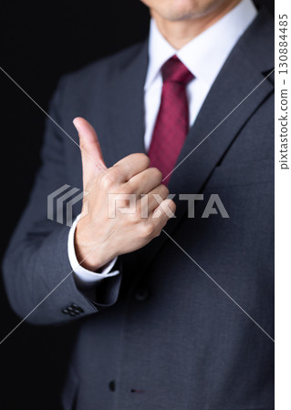 Middle-aged male businessman in a suit showing thumbs up 130884485