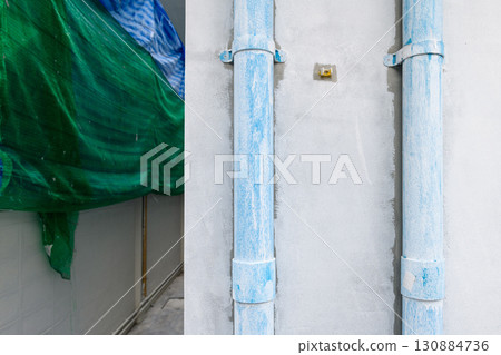 Functional detail of house renovation showing raw construction work in progress. Blue plastic plumbing pipes mounted on concrete wall for new utility installation 130884736