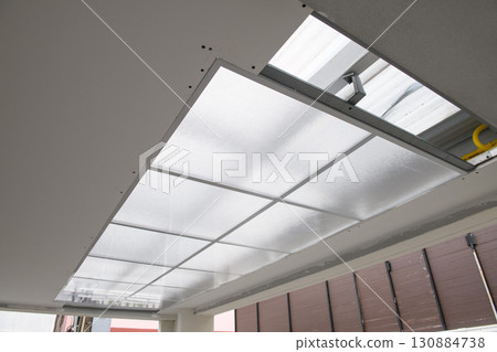 Focused detail on ceiling light installation during house renovation project. construction work shows new electric fixture and panel getting fitted with precision 130884738