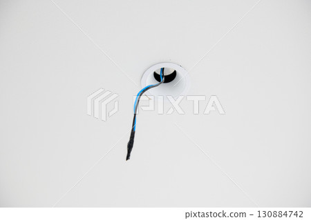 Close up detail of lone electric wire emerging from hole during house construction or renovation project showing sense of anticipation for completion 130884742