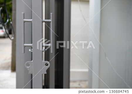 Secure metal gate detail during house renovation. modern construction provides safe entrance with simple lock mechanism adding to home calm exterior aesthetic Secure metal gate detail during house renovation. modern construction provides safe entrance with simple lock mechanism adding to home calm exterior aesthetic 130884745
