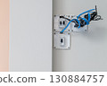 Close up detail of messy electrical wiring during house construction. An open junction box on wall shows complex process of home renovation and electrical work 130884757