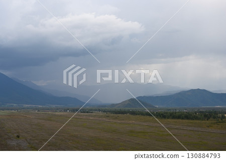 Heavy thunder clouds floating over the valley and mountains 130884793