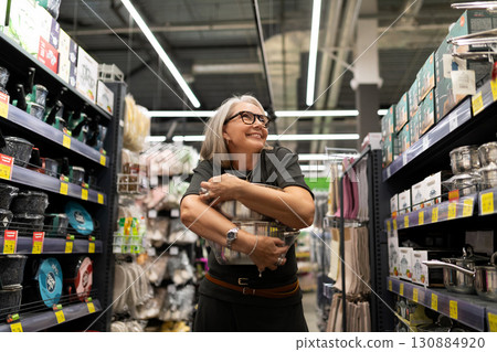 Happy woman shopping for kitchen supplies in a home goods store during the afternoon 130884920