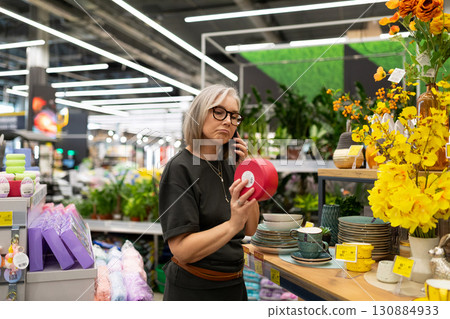 Woman shopping in a modern store, evaluating home decor items during a bright afternoon Woman shopping in a modern store, evaluating home decor items during a bright afternoon 130884933