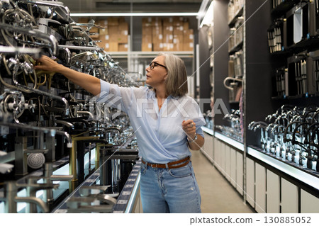 Searching for the perfect kitchen faucet in a modern home improvement store 130885052