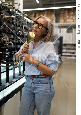 Woman exploring vintage telephones in a modern retail store during the afternoon 130885054