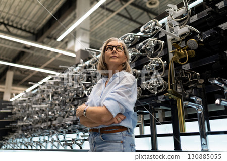 Experienced woman in a modern factory showcasing advanced machinery and technology during daytime 130885055