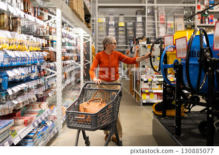 Woman shopping in hardware store for tools and home improvement supplies during daytime 130885077