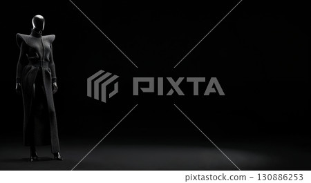 A sleek black faceless mannequin wearing a long, dark, high-fashion coat with exaggerated shoulders stands elegantly on a spotlighted dark stage, featuring ample copy space. 130886253