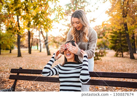 Surprising a friend with joy in a beautiful autumn park setting Surprising a friend with joy in a beautiful autumn park setting 130887674