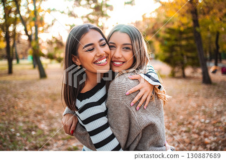 Celebrating autumn friendship between two girls in a colorful park Celebrating autumn friendship between two girls in a colorful park 130887689