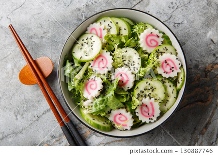 Narutomaki salad with cucumber, lettuce and sesame dressing close-up in a bowl. horizontal top view Narutomaki salad with cucumber, lettuce and sesame dressing close-up in a bowl. horizontal top view 130887746