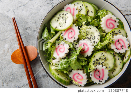 Low calorie Japanese salad with narutomaki fish roll, cucumber, lettuce and sesame dressing close-up in a bowl. horizontal top view 130887748