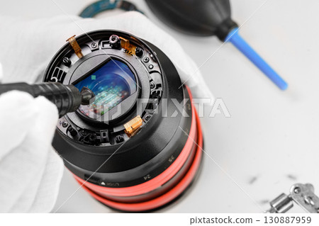 the hands of the master with gloves and a broken lens of a professional camera. the hands of the master with gloves and a broken lens of a professional camera. 130887959
