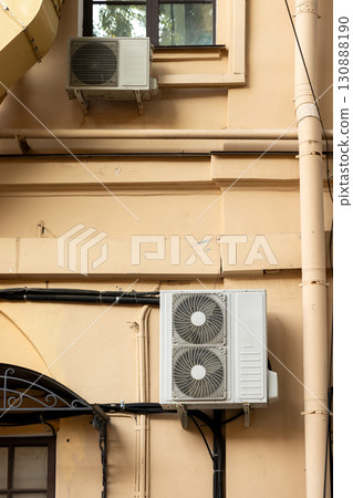 Air conditioners on the facade of yellow historical house. An air ventilation and cooling system. 130888190