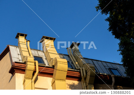 building with three chimneys on the roof. chimneys are yellow and the roof is brown.  130888201