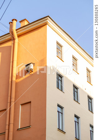 Air conditioners on the facade of a yellow house against a blue sky. An air ventilation. 130888265
