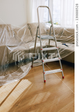 Aluminum step ladder in a living room with furniture 130888528
