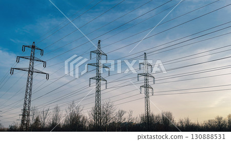 Electric power transmission towers and cables silhouetted Electric power transmission towers and cables silhouetted 130888531