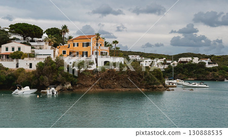 Coastal villa with orange walls and white details overlooking a calm bay. Menorca, Mahon 130888535