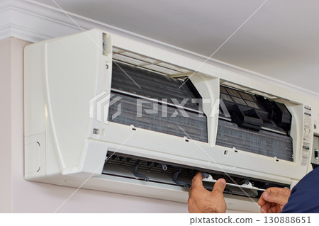 male hand of worker from the cleaning service cleans or repairs the air conditioner , close-up 130888651