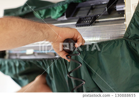 male hand of worker from the cleaning service cleans the air conditioner by spraying water, close-up male hand of worker from the cleaning service cleans the air conditioner by spraying water, close-up 130888655