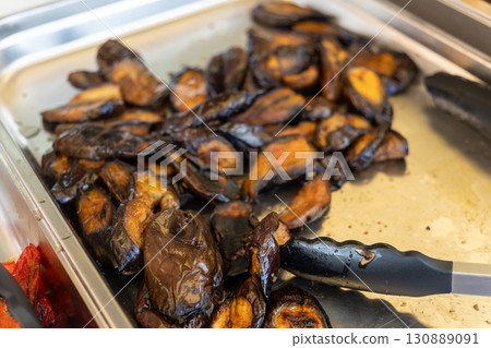 Baked eggplants on a tray at a barbecue buffet. Baked eggplants on a tray at a barbecue buffet. 130889091